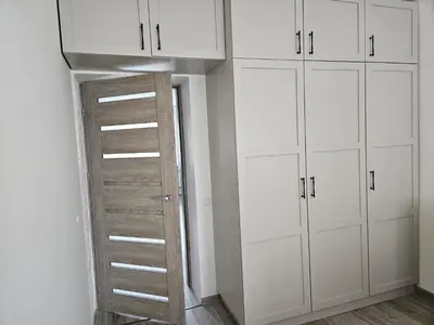 a closet with white cabinets and a ladder at Draugyste Apartment in Šiauliai