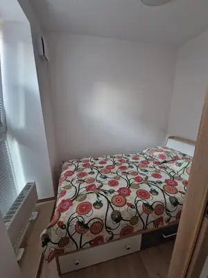 a small bedroom with a bed with a floral bedspread at Jaukus butas Pašilaičiuose in Vilnius