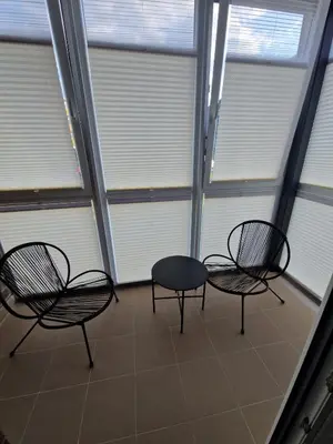 three chairs and a table in a room with windows at Jaukus butas Pašilaičiuose in Vilnius