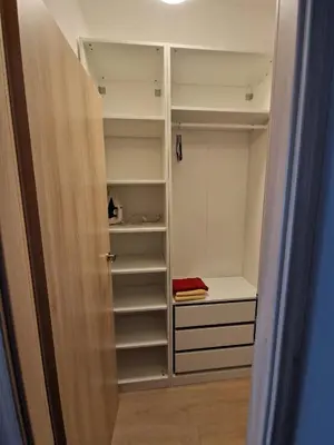 a closet with white cabinets and a red towel at Jaukus butas Pašilaičiuose in Vilnius