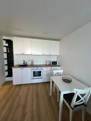 a kitchen with white cabinets and a table with chairs at Modern&bright southwest apartment in Šiauliai