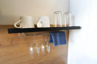 a black shelf with wine glasses and towels at Amber Light Self-Check-In Apartments in Kaunas