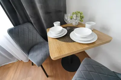 a wooden table with plates and wine glasses on it at Amber Light Self-Check-In Apartments in Kaunas