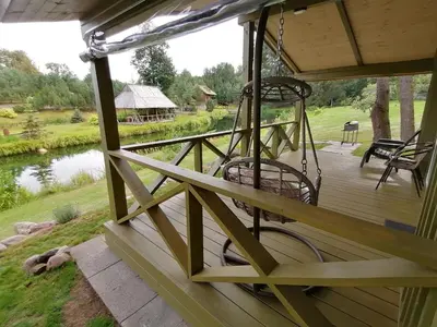 a porch with swings and a view of a pond at Jaučio apartamentai in Leliūnai