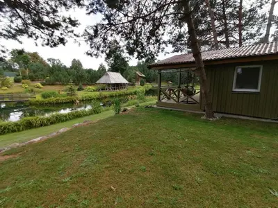 a house with a gazebo next to a lake at Jaučio apartamentai in Leliūnai