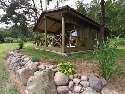 a small cabin with a rock wall in front of it at Jaučio apartamentai in Leliūnai