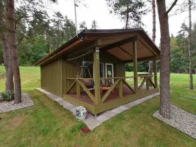 a green gazebo in a park with trees at Jaučio apartamentai in Leliūnai