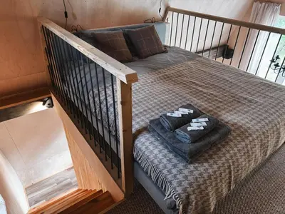 a bedroom with a bed with a wooden stair case at Mulberynas in Stakliškės