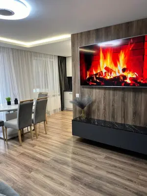 a living room with a fireplace and a table and chairs at Jaukūs , modernūs apartamentai in Raseiniai
