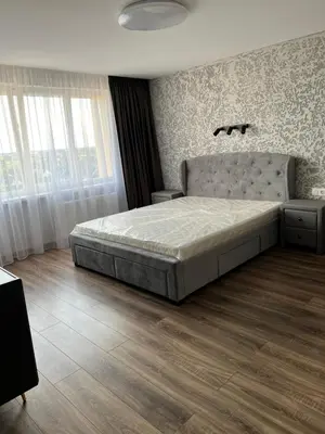 a bedroom with a large bed and a wooden floor at Jaukūs , modernūs apartamentai in Raseiniai