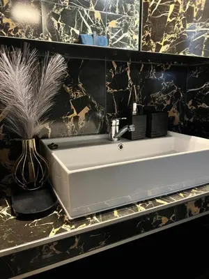 a white sink in a black and gold bathroom at Jaukūs , modernūs apartamentai in Raseiniai