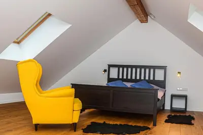 a bedroom with a bed and a yellow chair at Rami erdvė šalia miško ir ežero darbui ir poilsiui in Trakai
