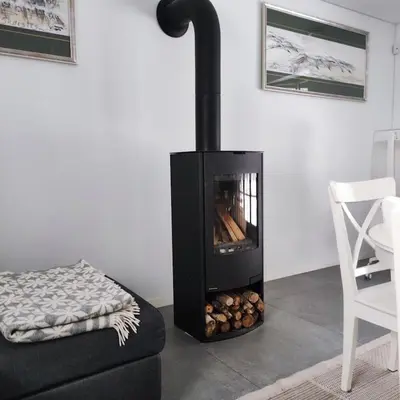 a black fireplace in a living room with a chair at Rami erdvė šalia miško ir ežero darbui ir poilsiui in Trakai