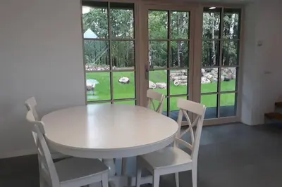 a white table and chairs in a room with windows at Rami erdvė šalia miško ir ežero darbui ir poilsiui in Trakai