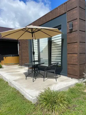 a table and chairs under an umbrella on a patio at Pas Alksnius in Šiaudinė