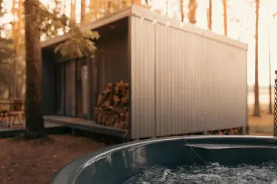a tub in front of a house with a building at Miško terapija in Kriviliai