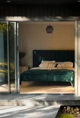 a bedroom with a bed with a green headboard at Miško terapija in Kriviliai