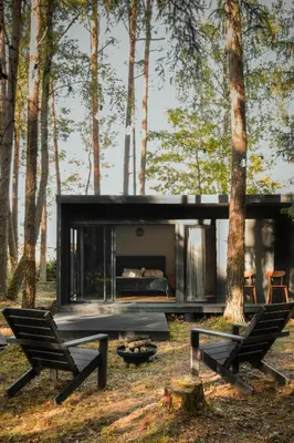 a modern house in the woods with two chairs and a fireplace at Miško terapija in Kriviliai
