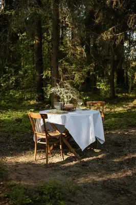 a table with a white table cloth and chairs at Miško terapija in Kriviliai