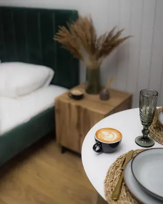 a table with a cup of coffee next to a bed at Miško terapija in Kriviliai