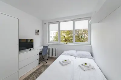 a white bedroom with a bed and a desk at Pramonės apartment #2 by PoloApartments in Kaunas
