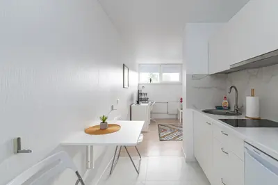 a white kitchen with a table and a sink at Pramonės Apartment #5 by PoloApartments in Kaunas