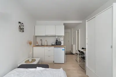 a small kitchen with white cabinets and a white refrigerator at Pramonės Apartment #6 by PoloApartments in Kaunas