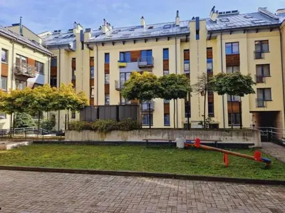 a large yellow building with trees in front of it at Sv1 Amber Oldtown SELF CHECK-IN by QuarterStays in Vilnius