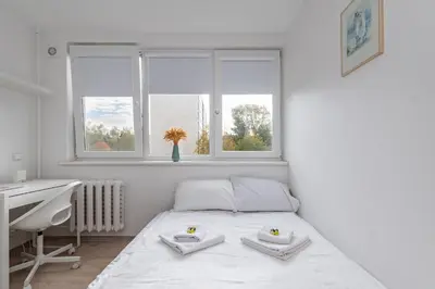 a white bedroom with a bed and a desk and windows at Pramonės Apartment #8 by PoloApartments in Kaunas