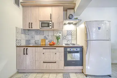 a kitchen with wooden cabinets and a refrigerator at Elegant apartment in Old town Vilnius SELF CHECK IN 24x7 by H&H in Vilnius