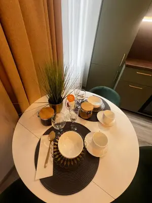 a white table with plates and glasses on it at Chic Residence apartament 1 in Šiauliai
