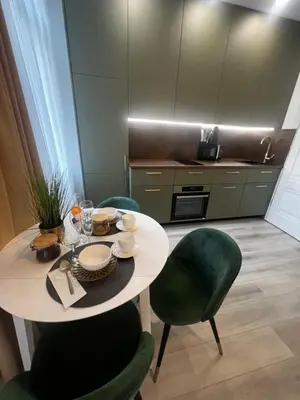 a kitchen with a table and green chairs and a table and chairsktop at Chic Residence apartament 1 in Šiauliai