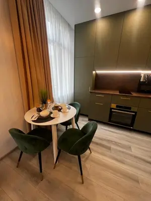 a dining room with a table and two green chairs at Chic Residence apartament 1 in Šiauliai