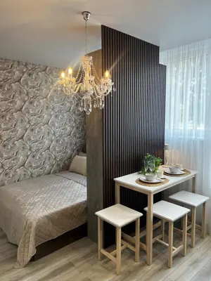 a bedroom with a bed and a table and a chandelier at Chic Residence apartament 2 in Šiauliai
