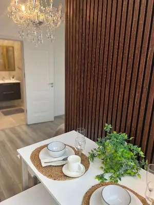 a dining table with a chandelier and a white table with plates at Chic Residence apartament 2 in Šiauliai
