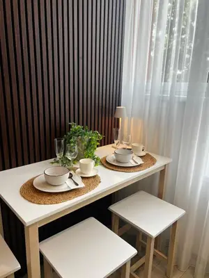 a white table with two chairs and a table with cups and plates at Chic Residence apartament 2 in Šiauliai
