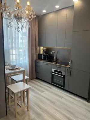 a kitchen with a chandelier and a kitchen with a table at Chic Residence apartament 2 in Šiauliai