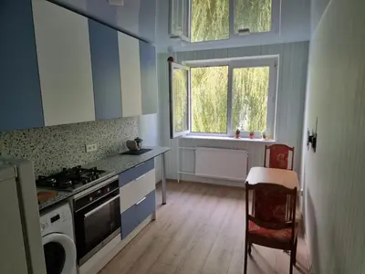 a kitchen with a stove and a sink and two windows at Kaunas 174 in Murava
