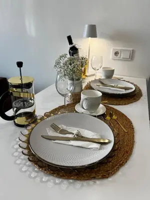a table with plates and silverware on a table at Chic Residence apartament 4 in Šiauliai