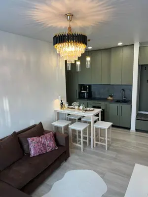 a living room with a couch and a kitchen with a chandelier at Chic Residence apartament 4 in Šiauliai