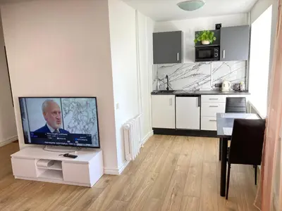 a living room with a flat screen tv and a kitchen at White & Black in Šiauliai