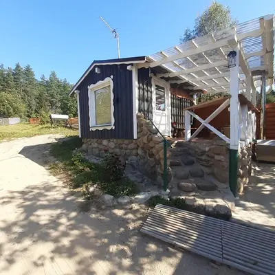 a small house with a white pergola next to a road at Dvivietis namelis su ofuro vone in Esperanza