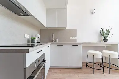 a white kitchen with white cabinets and bar stools at Loft G57 in Vilnius