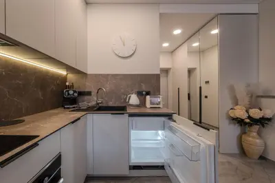 a kitchen with white cabinets and a clock on the wall at Old Town - Bajor Studios - Self Check-in and Parking in Kaunas