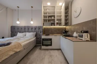 a small bedroom with a bed and a kitchen at Old Town - Bajor Studios - Self Check-in and Parking in Kaunas