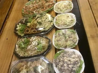 a table topped with trays of different types of food at Pirtis su kubilu ant ežero kranto Birvarelax in Kariotiškės