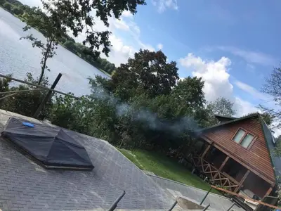 a house with smoke coming out of its roof at Pirtis su kubilu ant ežero kranto Birvarelax in Kariotiškės