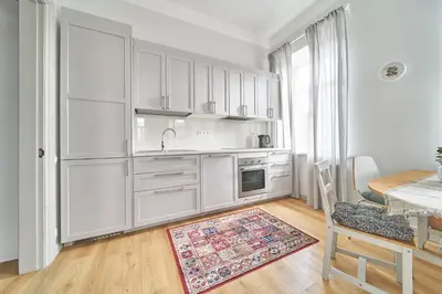 a kitchen with white cabinets and a table with a rug at Cute&Light Apartment, Vilnius City Centre in Vilnius