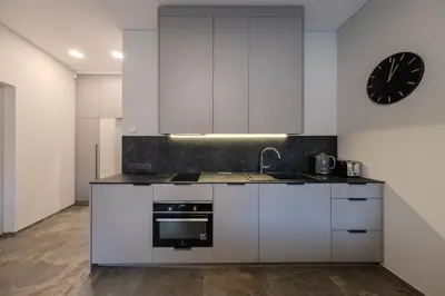 a kitchen with white cabinets and a clock on the wall at Old Town - Bajor Studios 2 - Self Check-in and Parking in Kaunas