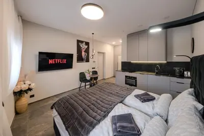 a bedroom with a large bed and a kitchen at Old Town - Bajor Studios 2 - Self Check-in and Parking in Kaunas
